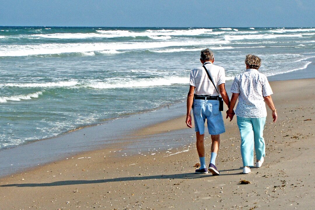retired couple walking on beach
