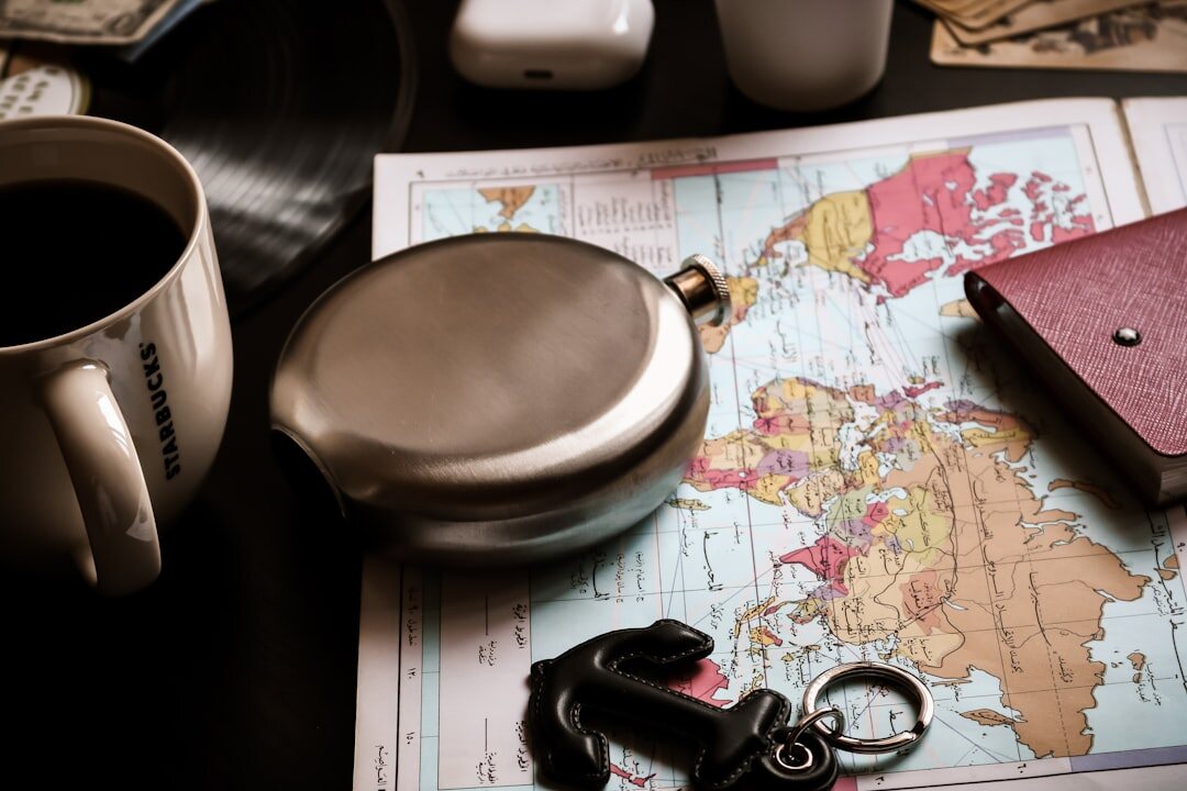 Person planning a relocation route on a world map with a laptop and coffee